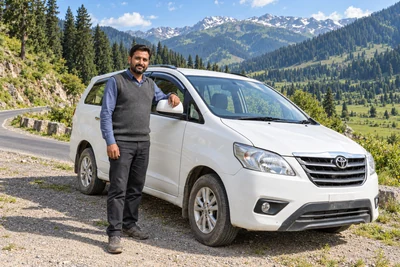 A Kashmiri driver in everyday clothing beside a white cab in a green valley